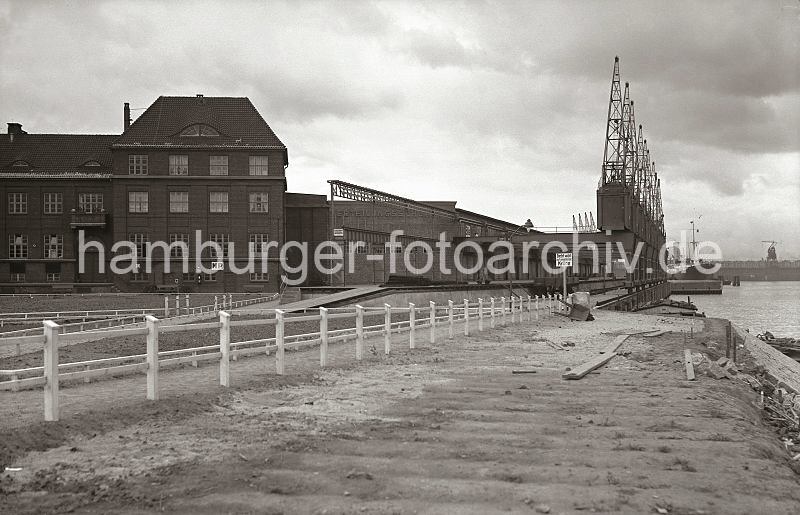 Historische Hafen-Bilder aus Hamburg. Verteilungsschuppen 58 Togokai - Halbportalkrananlagen am Suedwesthafen; ca. 1934. 622_21_B_245 Die Kainlage des Togokais ist fertig gestellt und der Verteilungsschuppen 57/58 erweitert. An der Stirnseite des Schuppengebudes ist der Schriftzug "Verteilungsschuppen" angebracht. ber die Laderampe und die Gleisanlage der Hafenbahn spannen sich die Halbportale der Hafenkrane, die mit Rdern in Schienen auf dem Kai und an der Fassade des Lagerschuppens gefhrt werden.