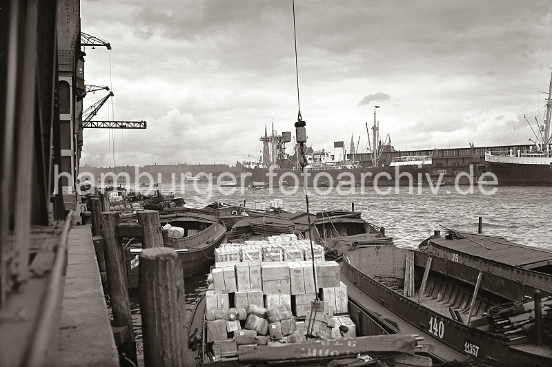 Historische Hamburg - Bilder aus dem Fotoarchiv der Hamburger HHLA. Schuten am Togokai des Indiahafens - Fracht im Laderaum der Lastkhne; ca. 1936.  624_B_248 Am Togokai des Indiahafens liegen die Schuten dicht an dicht. Im Vordergrund einer der Lastkhne ohne eigenen Antrieb mit hoch bepackten Laderaum. Kisten und Ballen ragen ber die Bordwand hinaus. An einem Kranhaken hngt eine Ladung Kartons. Im Hintergrund rechts Frachtschiffe am Australiakai.