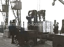 630_03502_30 Mit Hilfe eines Hubwagens wurde die groe Holzkiste aus dem Lagerschuppen auf den Hafenkai gefahren. Dort bereiten zwei Hafenarbeiter die Kiste fr die Verladung vor. Auf der Stirnseite der Kiste ist u.a. die Bezeichnung "Made in Germany" und der Bestimmungsort "New York" gedruckt.