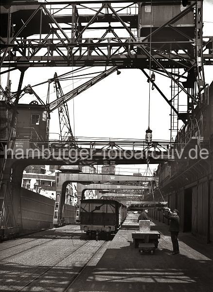 Ladung Kupferbarren lschen - Hamburger Hafen; ca. 1932. Alte Fotografien von der Arbeit im Hamburger Hafen aus dem - Bildarchiv der HHLA.  633_55 Eine Ladung Kupperbarren wird von dem am Hafenkai liegenden Frachter gelscht. Mit dem Kran werden die Metallbarren von Bord geholt und auf einem Elektroschlepper abgelegt. Ein Hafenarbeiter steht auf dem Fhrerstand des Elektrokarrens, ein anderer fhrt die am Kranhaken hngenden Barren zur Ladeflche.