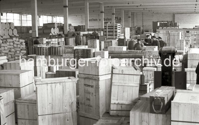Lagerschuppen 75 im Hamburger Kaiser-Wilhelmhafen / Kronprinzenkai; ca. 1952. Alte Fotografien von der Arbeit im Hamburger Hafen aus dem - Bildarchiv der HHLA.  639_4 Blick in den dicht gefllten Lagerschuppen 75 am Kronprinzenkai des Hamburger Kaiser-Wilhelm-Hafens. Kisten, Pakete und Ballen sind in dem groen Lagerraum gestapelt. Im Vordergrund stehen Holzkisten, die ber Perus Hafenstadt Callao nach Lima exportiert werden sollen. Rechts im Hintergrund stehen Kartons mit Glhbirnen, die den Aufdruck Osram tragen.