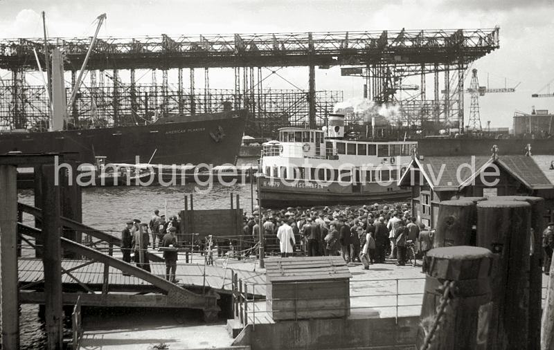 Historische  Bilddokumente vom Hamburger Hafen. Hafenfhre und wartende Hafenarbeiter am Anleger Rohft; ca. 1948.  647_1 Die Hafenarbeiter haben Feierabend, dicht gedrngt stehen sie auf dem Anleger Rosshft. Die Hafenfhre "Wischhafen" ist gerade beim Anlegemanver, um die Fahrgste an Bord zu nehmen. Im Rosshafen liegt der Frachter "American Planter", ein Binnenschiff hat lngsseits festgemacht. Im Hintergrund die Helgen der Howaldtswerft, die bis 1928 als Vulkanwerft gefhrt wurde.