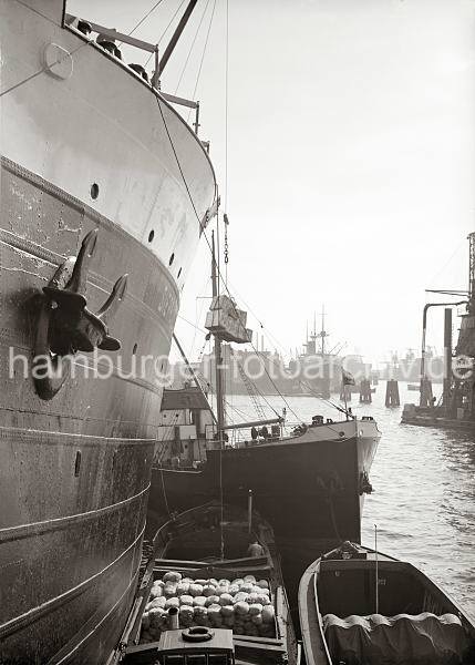 Historische  Fotodokumente vom berseehafen Hamburg. Gterumschlag im Hansahafen, O'swaldkai; ca. 1934. 655_682a Ein Frachter liegt am O'swaldkai des Hansahafens - auch wasserseitig werden Gter umgeschlagen. Eine Hieve Kisten hngt ber einer Schute. Im Hintergrund das Hansahft und die Einfahrt zum Indiahafen.