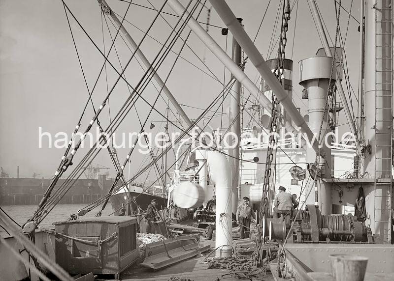 Frachtschiff im Hamburger Hafen - Ladebume; ca. 1934 657_683a Blick ber das Deck eines Frachter im Hamburger Hansahafen. Die Ladebume werden genutzt, um die wasserseitig liegenden Schuten und Schiffe zu beladen oder Ladung an Bord zu nehmen.