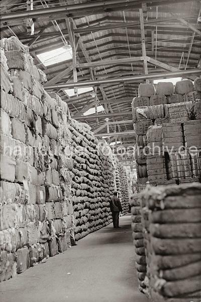 Fotodokumente der HHLA zur Geschichte des Hafens.Speicher + Wolllager im Hamburger Hafen; ca. 1934. 678_370 In einem Speicher im Hamburger Hafen sind Wollballen und andere Gter in Scken bis unter das Dach gestapelt. Ein Lagerarbeiter geht durch den Gang zwischen der Lagerware.