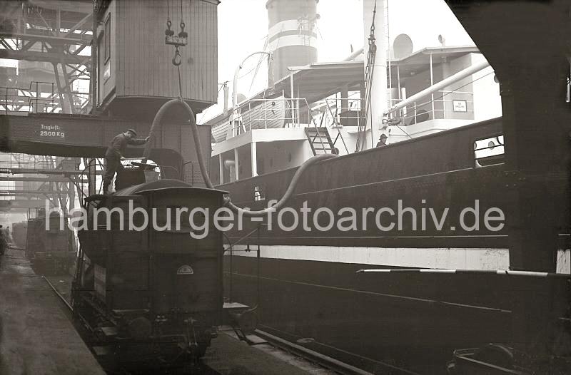 Historische Hafen-Fotos aus dem Archiv der Hamburger Hafen und Logistik AG (HHLA) Kesselwagen der Hafenbahn - Befllung des Schiffstanks.  689_B_327a ber einen Kesselwagen der Hamburger Hafenbahn werden mit einem dicken Schlauch die Tanks des Frachtschiffs befllt. ber den Kran wird der Schlauch in seiner Position gehalten, ein Arbeiter kontrolliert den Vorgang.