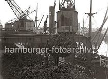 690_148 Lschen von Farbhlzern im Hamburger Hafen - der Rohstoff wird in einem Transportnetz mit dem Kran an Land gebracht und auf der Kaiflche abgelegt.