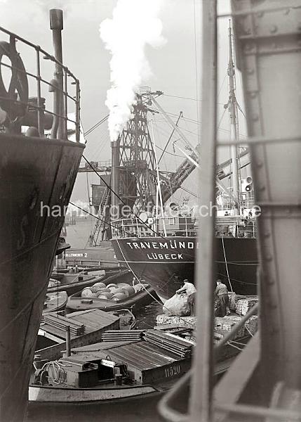 Historische Archivbilder der HHLA Gterumschlag im Hamburger Hafen;  ca. 1934. 703_800a Frachtschiffe liegen an einem Kai des Hamburger Hafens, ihre Ladung wird gelscht. Der Gterumschlag auch wasserseitig vorgenommen, auf Schuten, die die Waren im Hafengebiet verteilen, werden Kisten Fsser und Ballen verladen. Eine der Holztonnen schwebt am Ladebaum des Frachters TRAVEMNDE - in der Schute steht der Ewerfhrer im Laderaum und wartet auf die Hieve. Auch der KOHLENHEBER  2 arbeitet lngsseits des Ostseefrachters.