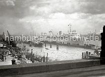 709_364 Blick von der Hochbahnstation Landungsbrcken auf den Niederhafen und Johannisbollwerk. Lks. die Kaischuppen der Hamburg Rhein Linie - unter den Halbportalkrnen stehen Lastwagen an der Rampe. Binnenschiffe und Schuten haben am Kai fest gemacht. Im Hintergrund das Dach und der Turm des Kaispeichers A. Am Ponton liegt das 1937 gebaute Passagierschiff Wilhelm Gustloff, das von der national- sozialistischen Organisation "Kraft durch Freude Kdf" als Kreuzfahrtschiff genutzt wurde.