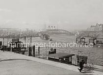 713_745a Blick vom Kehrwieder zum Brandenburger Hafen und Niederhafen; ein groes Schild auf dem Dach einer Holzhtte am Kai weist auf JOLLENFHRER hin. An den Dalben im Hintergrund und an der Kaimauer der Vorsetzen liegen Schlepper und Barkassen.