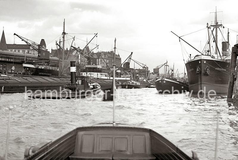 Hamburg Bilder zur Hafengeschichte Gterumschlag am Hafenkai - Hamburg Fotos Schiffsverkehr; ca. 1934. 716_2_379a Geschftiges Treiben an den Kaianlagen beim Johannisbollwerk; die Ladung des Motorschiffs LEVERKUSEN wird gerade gelscht - eine Hieve Kisten hngt am Kran. Kaiarbeiter nehmen die Ladung auf der Rampe an des Rheinkaischuppens an - Elbkhne und Binnenschiffe haben lngsseits der Frachtschiffe festgemacht. Hinter den Dchern der Kaischuppen und Hafenkrne die Wohnhuser am Johannisbollwerk.