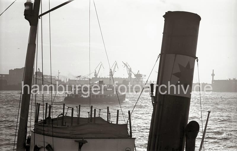 Nachkriegsfotos aus dem Hamburger Hafen - Archiv der HHLA. Blick ber die Elbe zur Werft Blohm & Voss; 1955. 719_2 Eine Hafenfhre der Hadag fhrt auf der Elbe Richtung Landungsbrcken - im Hintergrund Krne der Hamburger Werft Bohm & Voss.