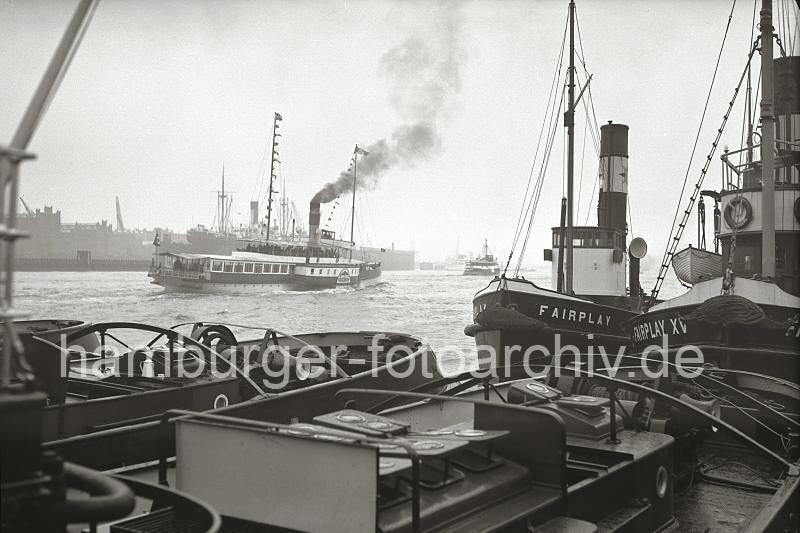 Hamburgensien als Geschenk fr Bro, Schlepper FAIRPLAY am Anleger - Raddampfer auf der Elbe; ca. 1936.  731_B_236 Blick ber die Decks der Hafenschlepper am Anleger; re. der Bug der Schlepper FAIRPLAY und FAIRPLAY XV. Auf der Elbe fhrt ein Raddampfer unter Dampf, am Oberdeck stehen die Menschen dicht gedrngt. 