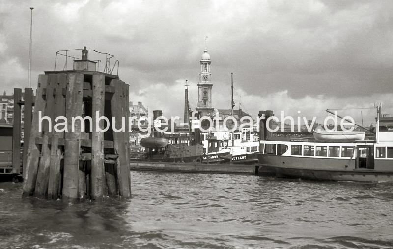 Hamburgensien als Geschenk fr Brojubilaeum,  Holzdalben - Dckdalben bei den Vorsetzen; Schlepper und Hafenfhre; 1952.  732_1 Lks. die typischen Hamburger Duckdalben - ein Pfahlbndel das tief in die Sohle des Hafens eingerammt wird. An ihnen werden Seeschiffe vertut. Im Hintergrund die Schlepper MATADOR und KRAUTSAND. Der Turm der St. Michaeliskirche, dem Hamburger Wahrzeichen ragt aus  den Schiffen des Hamburger Hafens heraus.