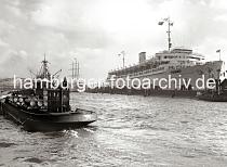 733_364a Im Vordergrund transportiert ein Hafenfahrzeug der Deutschen Vacuum Oel AG Fsser. Die WILHELM GUSTLOFF hat am Anleger fest gemacht - Arbeiter hngen auf Plattformen vor dem Bug des Schiff und streichen die Bordwand. 