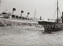 742_399 Am Passagierschiff CAP ARCONA hat eine Schute lngsseits festgemacht - ber das Ladegeschirr des Dampfers werden Gter an Bord gehievt. Das Frachtschiff LOTHAR mit Heimathafen Hamburg luft in den Hafen ein.