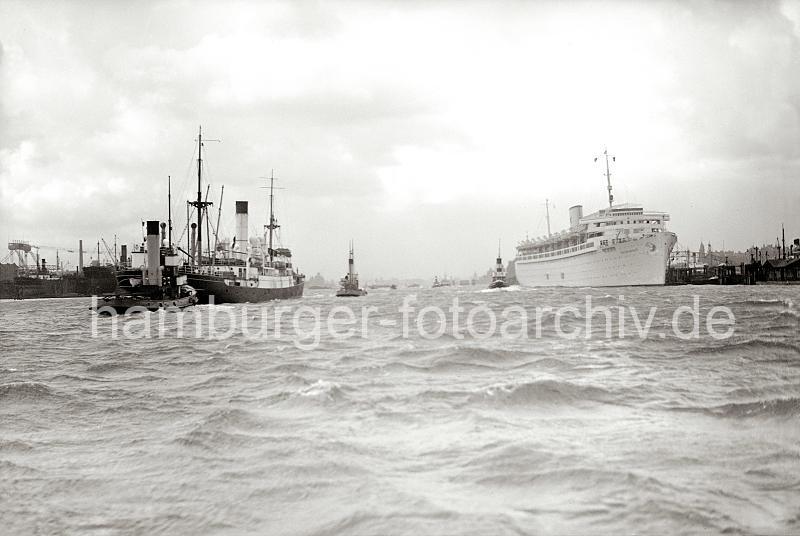 Alte Schiffsfotos aus Hamburg - Schiffe im Hamburger Hafen - Kreuzfahrtschiff WILHELM GUSTLOFF, Frachter mit Schlepper; ca.1938.  745_363a Ein Motorschiff luft aus dem Hamburger Hafen aus. Mit Hilfe von Hafenschleppern fhrt das Frachtschiff im Strom der Elbe in Hhe der berseebrcke. Rechts liegt das Kreuzfahrtschiff Wilhelm Gustloff am Ponton - das 1938 fertig gestellte  Passagierschiff kann 1 463 Passagiere an Bord nehmen. Der Passagier-Dampfer wurde von der national- sozialistischen Organisation "Kraft durch Freude Kdf" als Kreuzfahrtschiff genutzt.