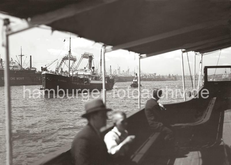 Historische Hamburgbilder aus Hamburg - Hafenfhre und Frachtschiff vor der DEUTSCHEN WERFT.  756_3_614 Blick vom Fahrgastraum einer Hafenfhre auf die Elbe - das Frachtschiff OLDENBURG luft in den Hafen Hamburgs ein. Die Ladung ist hoch an Deck des Frachters gestapelt. Am Elbufer von Steinwerder ragen die Portale der Kabelkrne der DEUTSCHEN WERFT empor - Schiffe liegen zur Reparatur und berholung in den Docks.