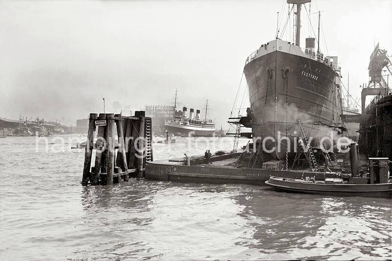 Alte Schiffsfotos aus Hamburg Frachter FLOTTBEK im Schwimmdock. 757_399a Der Frachter FLOTTBEK liegt eingedockt im Trockendock. Werftarbeiter stehen auf Leitern und Gersten und arbeiten am Schiffsrumpf.  Im Hintergrund die Einfahrt zum Grasbrookhafen.