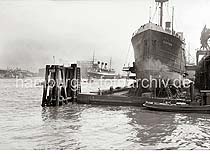 757_399a Der Frachter FLOTTBEK liegt eingedockt im Trockendock. Werftarbeiter stehen auf Leitern und Gersten und arbeiten am Schiffsrumpf.  Im Hintergrund die Einfahrt zum Grasbrookhafen.