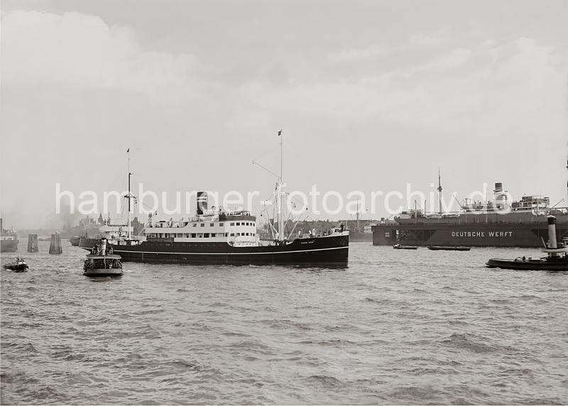 Hamburg Bilder als Geschenk - Schiffsbewegungen auf der Elbe - Schwimmdock Deutsche Werft; ca.1934. 763_627 Der 1923 gebaute norwegische Fracht- und Passgierdampfer KONG DAG auf der Elbe vor dem Schwimmdock der DEUTSCHEN WERFT am Reiherstieg - ein Ausflugsdampfer mit Fahrgsten an Bord lsst das Schiff passieren.