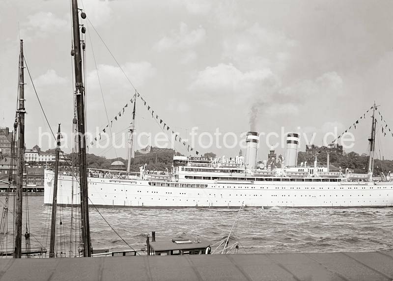 Alte Hamburger Hafenbilder als Praesent bei Einladung Firma - Geschftsfreunde - Kreuzfahrtschiff OCEANA vor den Hamburger Landungsbrcken; ca. 1936. 772_762a Das Passierschiff OCEANA verlsst ber die Toppen geflaggt den Hamburger Hafen aus - die Passagiere stehen an Deck und Blicken ber die St. Pauli Landungsbrcken. Im Hintergrund ist in der linken Bildmitte das Seemannshaus und auf der rechten Seite die Hamburger Seewarte auf dem Stintfang zu erkennen.