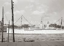 772_762a Das Passierschiff OCEANA verlsst ber die Toppen geflaggt den Hamburger Hafen - die Passagiere stehen an Deck des weien Schiffs und Blicken ber die St. Pauli Landungsbrcken. Im Hintergrund ist in der linken Bildmitte das Seemannshaus und auf der rechten Seite die Hamburger Seewarte auf dem Stintfang zu erkennen.