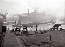 775_196 Der Turbinendampfer EUROPA wird von Schleppern aus dem Vorhafen auf die Elbe gezogen - luft aus dem Hamburger Hafen aus.  Mit einer Maschinenleistung von 130 000 PS konnte der Schnelldampfer mehr als 27 Knoten erreichen - so gewann das Schiff bei seiner Jungferfahrt, die 1930 von Bremerhaven aus nach New York starte gleich das Blaue Band. Diese Ehrung bekam das schnellste Schiff fr bezahlende Passagiere auf der Transatlantik-Route Europa-New York.