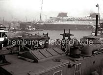 776_196a Der Passagierdampfer EUROPA wird von drei Schleppern von seinem Liegeplatz am Kai der Werft Blohm & Voss in den Vorhafen gezogen, um von dort aus seine Fahrt auf die Elbe aufzunehmen. Hinter dem Arbeitsschiff liegen Barkassen und Schiffe der Hafenrundfahrt mit Fahrgsten an Bord, die dem Schiffsmanver zusehen. 