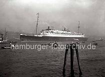 778_197a Das Luxus-Passagierschiff EUROPA beim Auslaufen aus dem Hamburger Hafen -  im Hintergrund Speicher und Industriegebude von Altona. Der 282,77m lange und 30,65m breite Turbinendampfer wird von Schleppern in die Fahrrinne der Elbe gezogen.