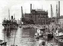 800_B_286 Im Altonaer Hafen liegen die Motorschiffe und Frachtsegler am Kai -  auf der Grossen Elbstrasse steht ein Pferdefuhrwerk und wartet auf Ladung; davor eine Tankstelle mit der Aufschrift "Essoclub". An der Wasserfront liegen die Gebude von HANIEL'S KOHLENHOF und das Elblagerhaus Wilh. Hausschild.Lastwagenanhnger werden ber ein Frderband mit Kohlen beladen.