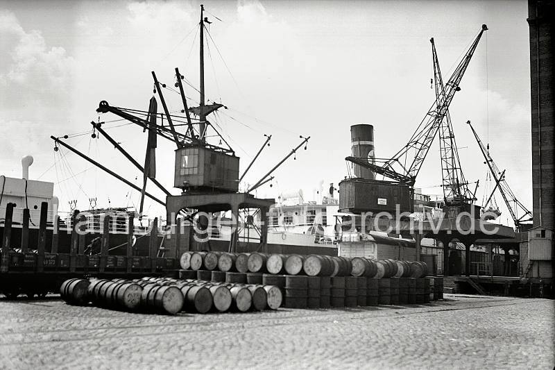 Alte Fotos Hamburg Altona - Gterumschlag am Kai vor dem Khlhaus Hamburg Neumhlen; 1938. Altonaer Fotografien auf FotoleinwandLeinwand + als Fotoposter.  817_B_290a Ein Kaikran hievt eine Ladung Scke auf das vor dem Neumhlener Khlhaus liegende Frachtschiff. Auf den Pflastersteinen des Hafenkais liegen Metallfsser, ein Teil ist in die bereit stehenden offenen Gterwagen / Rungenwagen verladen.