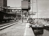 829_B_263 Mehrere groe Elbkhne und motorisierte Binnenschiffe liegen an der Kaimauer eines der drei Harburger Seehafenbecken. ber eine Sauganlage wird die Ladung der Schiffe gelscht und per Frderband in das Silo transportiert. Im Hintergrund die Sderelbe und Wilhelmsburger Industrieanlagen.