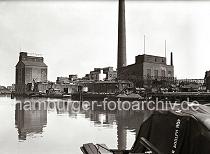 833_B_264 Fabrikationsanlage mit Silo und hohem Schornstein der "Thrl's Vereinigte Harburger lfabriken AG" im Harburger berwinterungshafen. Fsser liegen auf dem Kai, eine Schute wird ber eine Kippvorrichtung beladen - Kaiarbeiter fllen Scke, die auf eine Schute verladen werden. 