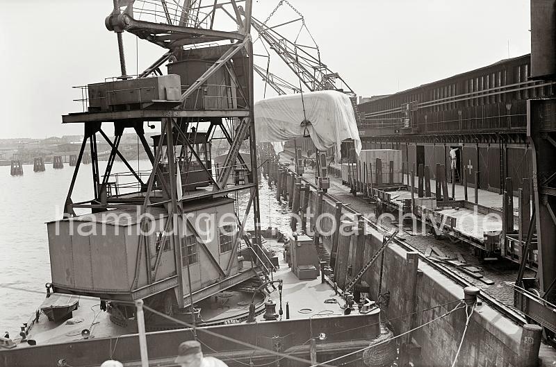 Historische Hamburg-Fotografie - Schwimmkran mit einem BSSING NAG Autobuss - Gterwagen / Rungenwagen; ca. 1937 - Alte Fotos als Geschenk zum Geburtstag, Jubilaeum + Weihnachten. 87_B_303a Der Schwimmkran, der eine Last bis 25 Tonnen transportieren kann, hat den 4800 kg schweren Autobus vom Gterwagen am Bremer Kai abgeladen. Die Halbportalkrne im Hansahafen knnen nur eine Last bis 3000 kg anheben - ein Schild am Portal der Krananlage weist auf diese Tragfhigkeit hin.  Im Hintergrund Lagerhuser am Lbeckerufer und Wohngebude von Hamburg Wilhelmsburg.