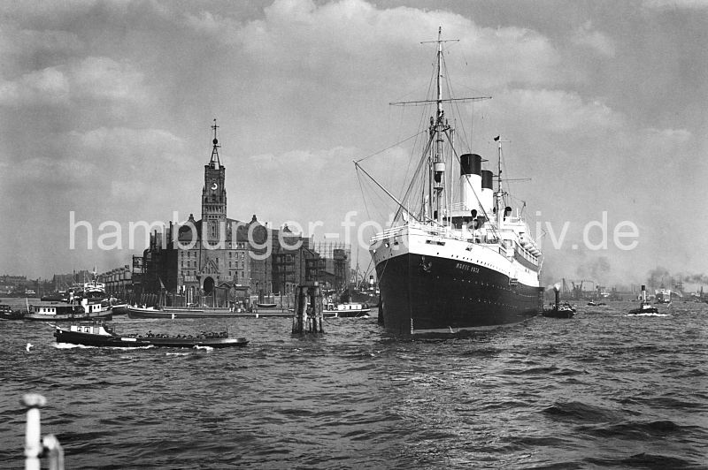 Bilder aus dem historischen Hamburger Hafen - Kaispeicher Passagierschiff Monte Rosa ca.1932.  172_0276 Der Passagierdampfer Monte Rosa hat an den Holzdalben in der Elbe fest gemacht. Das Schiff lief 1930 vom Stapel und wurde auf der Hamburger Werft Blohm & Vo gebaut. Eine Barkasse mit Hafenarbeitern fhrt Richtung Baumwall und ein Binnenschiff biegt in Sandtorhafen ein, dessen Hafenbecken links im Hintergrund zu erkennen ist. Auf dem Uhrturm des 1876 erbauten Kaiserspeichers /  Kaispeichers ist die Zeitballanlage zu erkennen, die von der Sternwarte am Millerntor ausgelst wurde. Der Ball hatte einen Durchmesser von einem Meter und wurde exakt Mittags um 12.00 Uhr weit sichtbar fallen gelassen.