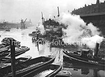 173_3502 Frachter liegen am Sandtorkai, Schuten haben lngsseits fest gemacht - ein Schlepper unter Dampf kommt vom Brooktorhafen und fhrt in den Sandtorhafen ein. Vor dem Kaiserkai wird ein Kohleheber von zwei Schleppern gezogen - im Hintergrund die Silhouette vom Kaiserspeicher und die Mndung des Hafenbeckens in die Elbe