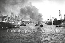 174_3502 Ein Frachter liegt am Versamannkai des Baakenhafens und wird entladen - der Schlepper zieht eine Schute in der Mitte des Hafenbeckens, dicker Qualm steigt aus seinem Schornstein. Rechts am Petersenkai liegt ein Schwimmkran und wartet auf seinen Arbeitseinsatz.