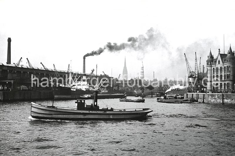 historische Hamburger Hafenfotos - Magdeburger Hafen 1931 - Fruchtschuppen  175_3502 Blick in den Magdeburger Hafen - ein Frachtschiff liegt am Fruchtschuppen C und wird entladen, der Schornstein hinter dem Schuppendach gehrt zum Gaswerk am Kleinen Grasbrook. Hinter der Baakenbrcke die Dcher der Hamburger Speicherstadt und die Kirchtrme der St. Nikolai und St. Katharinenkirche. Rechts das Backstein-Verwaltungsgebude vom Furchtschuppen am Versmannkai - ein Wasserboot ist mit Frischwasser auf seiner Versorgungsfahrt.