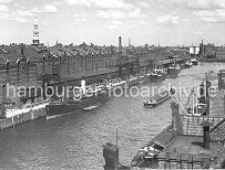 265_607a Blick vom Kaispeicher A in den Sandtorhafen; ein Frachter liegt am Sandtorkai und wird mit einem Halbportalwippkran entladen. Die gelschte Fracht wird in den Kaischuppen gelagert oder in die dahinter liegenden Lagerbden der Speicherstadt transportiert. Links im Hintergrund der Kirchturm der St. Jakobikirche und daneben die St. Katharinenkirche. Rechts die Backsteinarchitektur vom Kaispeicher B am Magdeburger Hafen. 