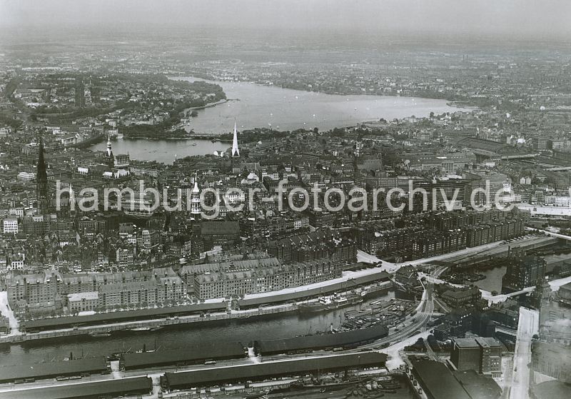 historische Luftaufnahme der Speicherstadt, Sandtorhafen u. Brooktorkai; Hamburger Innenstadt   266_0431 Luftaufnahme ca. 1930; ganz im Vordergrund ist ein Ausschnitt vom Grasbrookhafen mit den Lagerschuppen des Dalmannkais zu erkennen.  Dahinter der Sandtorhafen mit den Schuppen am Sandtorkai, die sich bis zur Brooktorschleuse hinziehen. Hinter der Schlickschleuse der Brooktorhafen und der Kaispeicher B. Hinter der hohen Backsteinarchitektur der Speicherstadt liegt die Hamburger Altstadt mit vier Hamburger Hauptkirchen St. Nikolaikirche, St. Katharinen, St. Petrikirche und die St. Jakobikirche (v. lks.) In Nhe der Binnenalster das Hamburger Rathaus mit Turm - Segelschiffe fahren auf der Aussenalster.