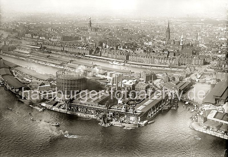 Luftaufnahme Hamburg - Gaswerke Grasbrook, Magdeburger Hafen, Grasbrookhafen, Sandtorhafen   267_2417 Luftaufnahme von dem Gaswerk auf dem Kleinen Grasbrook ca. 1936; rechts der Magdeburger Hafen mit seinen Fruchtschuppen und am unteren rechten Bildrand die Einfahrt zum Baakenhafen. Auf der linken Bildseite die Kaianlagen am Strandhafen, dann die Lagerschuppen am Hbnerkai und Dalmannkai des Grasbrookhafens. Lks. darber der Kaispeicher A und die Dcher der Lagerschuppen am Kaiserkai des Sandtorhafens. Entlang des Standtorkais erstrecken sich die westlichen Lagerhuser der Hamburger Speicherstadt, dahinter die Hamburger Neustadt und Teile der Altstadt mit den Kirchtrmen der St. Michaeliskirche, St. Nikolaikirche, St. Katharinenkirche (v. lks.). 