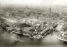 267_2417 Luftaufnahme von dem Gaswerk auf dem Grasbrook ca. 1930; rechts der Magdeburger Hafen mit seinen Fruchtschuppen und am unteren rechten Bildrand die Einfahrt zum Baakenhafen. Auf der linken Bildseite die Kaianlagen am Strandhafen, dann die Lagerschuppen am Hbnerkai und Dalmannkai des Grasbrookhafens. Lks. darber der Kaispeicher A und die Dcher der Lagerschuppen am Kaiserkai des Sandtorhafens. Entlang des Standtorkais erstrecken sich die westlichen Lagerhuser der Hamburger Speicherstadt, dahinter die Hamburger Neustadt und Teile der Altstadt mit den Kirchtrmen der St. Michaeliskirche, St. Nikolaikirche, St. Katharinenkirche (v. lks.).