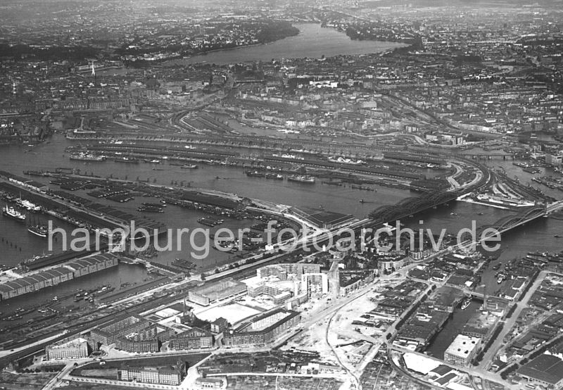 Luftbild der Hamburger Elbbrcken, Norderelbe, Baakenhafen und Veddel  269_2367 Luftaufnahme von Hamburg Veddel und Hafengebiet - im Vordergrund die unter dem Einfluss des damaligen Oberbaudirektor Fritz Schumacher entstanden Backstein-Wohnblocks auf der Veddel; rechts der Marktkanal, dahinter die Norderelbbrcke und die Freihafenelbbrcke.In der Bildmitte das lange Hafenbecken des Baakenhafen, rechts der Oberhafenkanal und Billehafen. Links der Moldauhafen an dessen Stirnseite das Dresdener Ufer an der Freihafengrenze liegt; dann der Saalehafen mit den Lagerhusern am Dessauer Ufer. Darber ist noch ein Ausschnitt vom Segelschiffhafen mit dem Asiakai und Segelschiffkai zu erkennen.