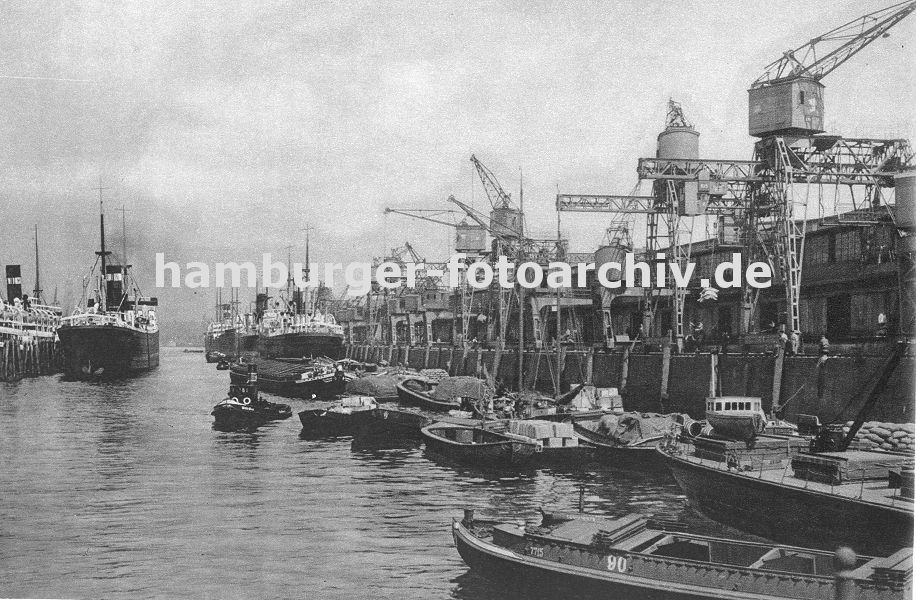 0953986 historische Bilder vom Hamburger Hafen - alte Fotos von der Hansestadt Hamburg :Blick ber den Indiahafen Richtung Elbe - re. der Australiakai mit den Lagerschuppen 52 und Schuppen 53. Auf dem Kai stehen Portalkrne und beladen oder entladen Schuten und Lastkhne, die mit Scken, Kisten oder anderer Fracht beladen sind. Frachter liegen an der Kaimauer, andere haben an den Holzpfhlen / Dalben in der Mitte des Hafenbeckens fest gemacht.