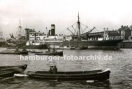 0954000 Fotos Geschichte Hamburger Hafen - Dokumentation, Schlepper ziehen jeweils zwei Schuten durch den Ellerholzhafen - ein Frachter liegt am Mnckebergkai und lscht seine Ladung auf lngsseits liegende Boote. Rechts im Hintergrund die im Hamburger Hafen typische Industriearchitektur mit Turm - das Gebude steht am Kronprinzenkai im Kaiser Wilhelm Hafen. 