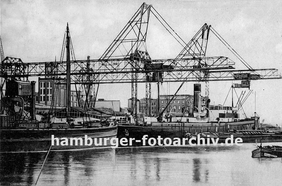 k_0954022 Frachtschiffe liegen im Harburger Seehafen am Kai - die Kranausleger sind heruntergelassen und beladen oder entladen die Schiffe. Eine Schute liegt am Dampfschiff lngsseits und wird mit bordeigenem Ladebaum  geladen; im Hintergrund Harburger Fabrikgebude.