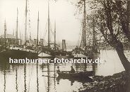 k_0954024 mehrere Fischkutter liegen bei den Landungsbrücken von Hamburg Finkenwerder - ein Ruderboot mit zwei Jungen an Bord liegt am Ufer. Im Hintergrund ein weiteres Ruderboot mit Kindern
