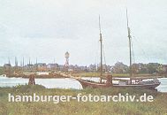 k_0954025 Blick ber das Khlfleet nach Finkenwerder; am Ufer liegt ein Segelschiff vor Anker, ein anderes hat den den Dalben fest gemacht. Im Hintergrund die Finkenwaerder Landungsbrcken an der eine Hafenfhre angelegt hat - zwischen den Husern Finkenwerders ragt der Wasserturm heraus. 