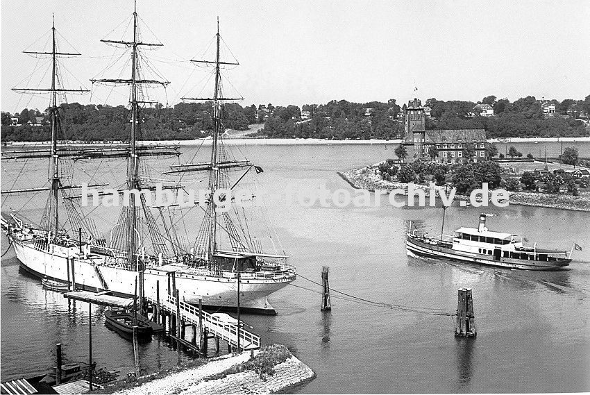 0954027 Blick von Finkenwerder Richtung Elbe ca. 1939; ein Segelschiff liegt am Steg - es ist mit Tauen an den Duckdalben fest gemacht. Eine Hafenfhre hat von den Finkenwerder Landungsbrcken abgelegt und fhrt Richtung Elbe. Dahinter ist das Hamburger Lotsenhaus zu erkennen, das vom Hamburger Oberbaudirektor Fritz Schumacher entworfen wurde. Am anderen Elbufer sind Huser an der Elbchaussee von Hamburg Othmarschen zu erkennen.